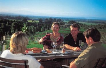 People drinking wine around outside table with scenic views