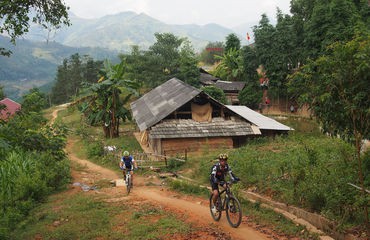 Cyclists riding along track past houses