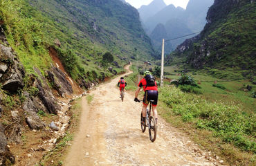 Cyclists riding up between mountains