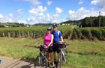 Couple on bikes posing in front of vineyard