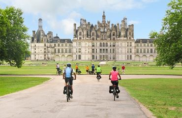 Cyclists riding towards a chateau
