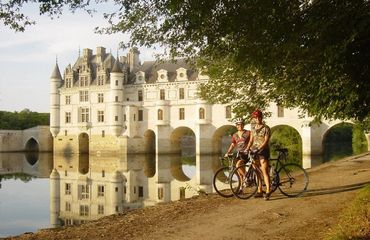 Cyclists resting by the side of a lake with chateau in background