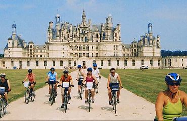 Group of cyclists riding towards camera with chateau in background