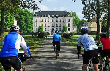 Cyclists riding down driveway to chateau