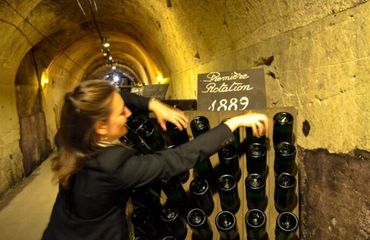 Woman twisting bottles in wine cellar