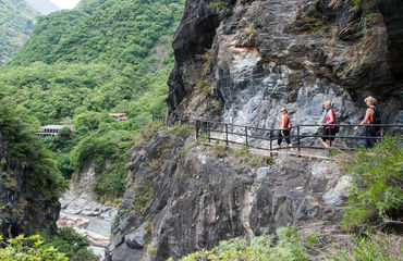 Hikers on a pathway along a cliff