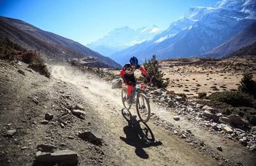 Cyclist riding along trail with mountains