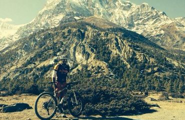Cyclist standing infront of mountain