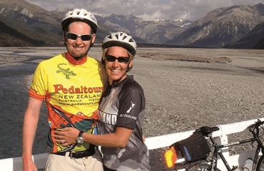 Couple of cyclists standing with mountains behind