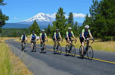 Line of cyclists riding along road with mountain in background