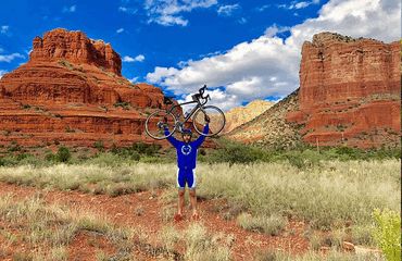 Cyclist holding his bike up in Arizonan rock setting