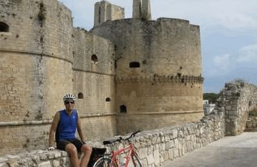 Cyclist resting on wall with bike by historic building