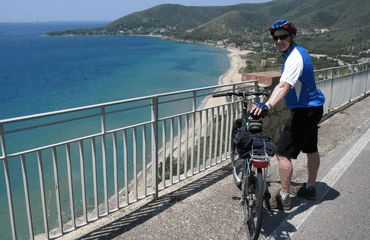 Cyclist standing at railing, looking at view
