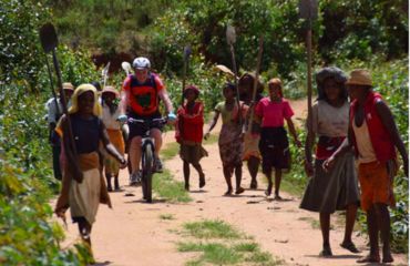 Cyclist riding along with female villages either side