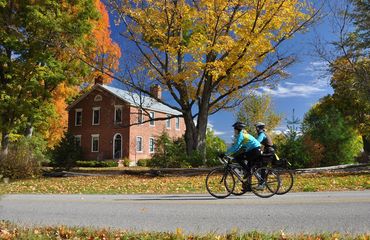 Cyclists on road with historic building and trees