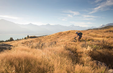Biker riding towards mountains and lake