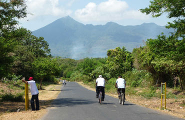 Cycling down road with volcano in background