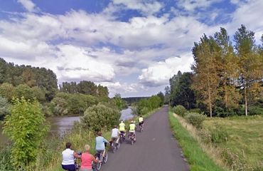 Cyclists riding along river bank