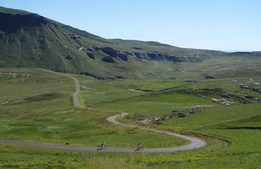 Cycling winding road at base of mountains