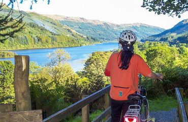 Cyclist standing at viewpoint over loch