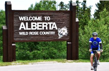 Cyclist infront of Alberta sign