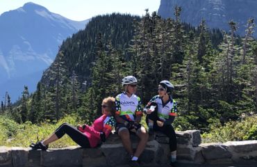 Cyclistss resting on wall by mountains