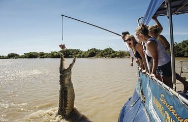 Crocodile jumping out of the water with people watching from boat