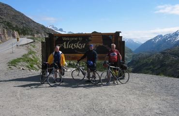 Cyclists standing by Alaska sign