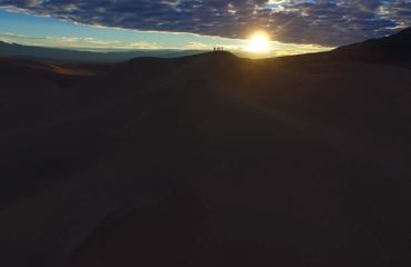 Silhouette of people far away on desert hill at sunset/sunrise