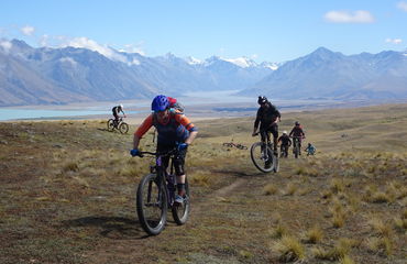 Bikers riding with mountains and lake behind