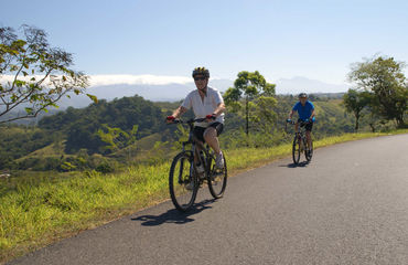 Cyclists riding along road with hilly backdrop