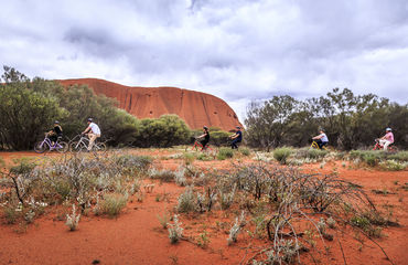 Cyclists riding by Uluru