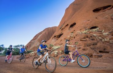 Family riding bikes round red rock