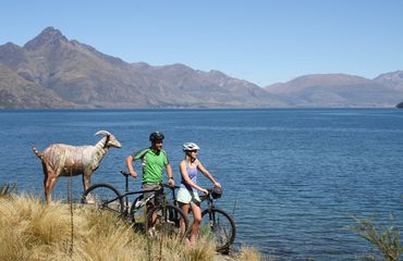 Statue of goat and cyclists by lake